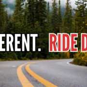 Background image of an open road winding through a forest with text: Think Different. Ride Different.